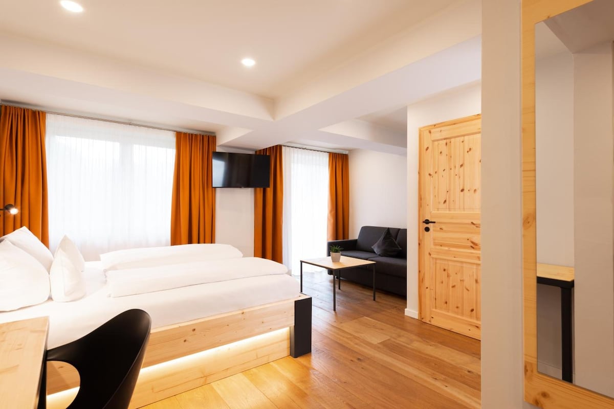 Ein modernes Hotelzimmer mit einem Bett, einem Schreibtisch, einem Fernseher und einer Couch.