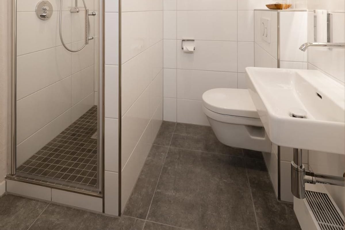 Ein modernes Badezimmer mit einer einteiligen Duschkabine, einer Toilette und einem Waschbecken.