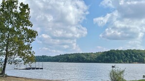 A picnic table by a lake with a dock and boat in the background.