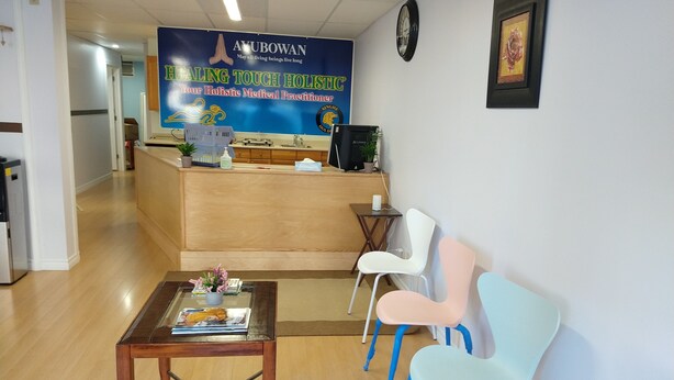 Uma área de recepção com uma mesa de madeira, balcão de atendimento e três cadeiras coloridas.