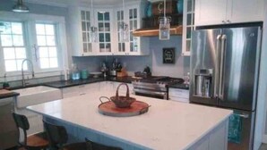 Cocina moderna con armarios blancos, un refrigerador de acero inoxidable y una isla central con asientos.