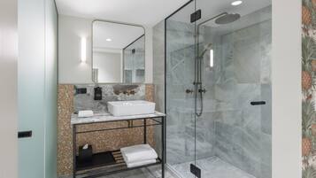 Un baño moderno con ducha de vidrio, lavamanos blanco y encimera de mármol.