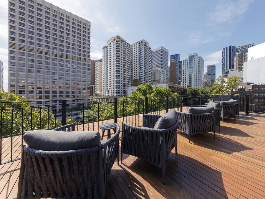 Terraza en la azotea con mobiliario de mimbre y vistas a edificios de la ciudad.