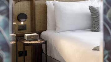Un dormitorio ordenado con cama, mesita de noche, lámpara y un cuadro en la pared.