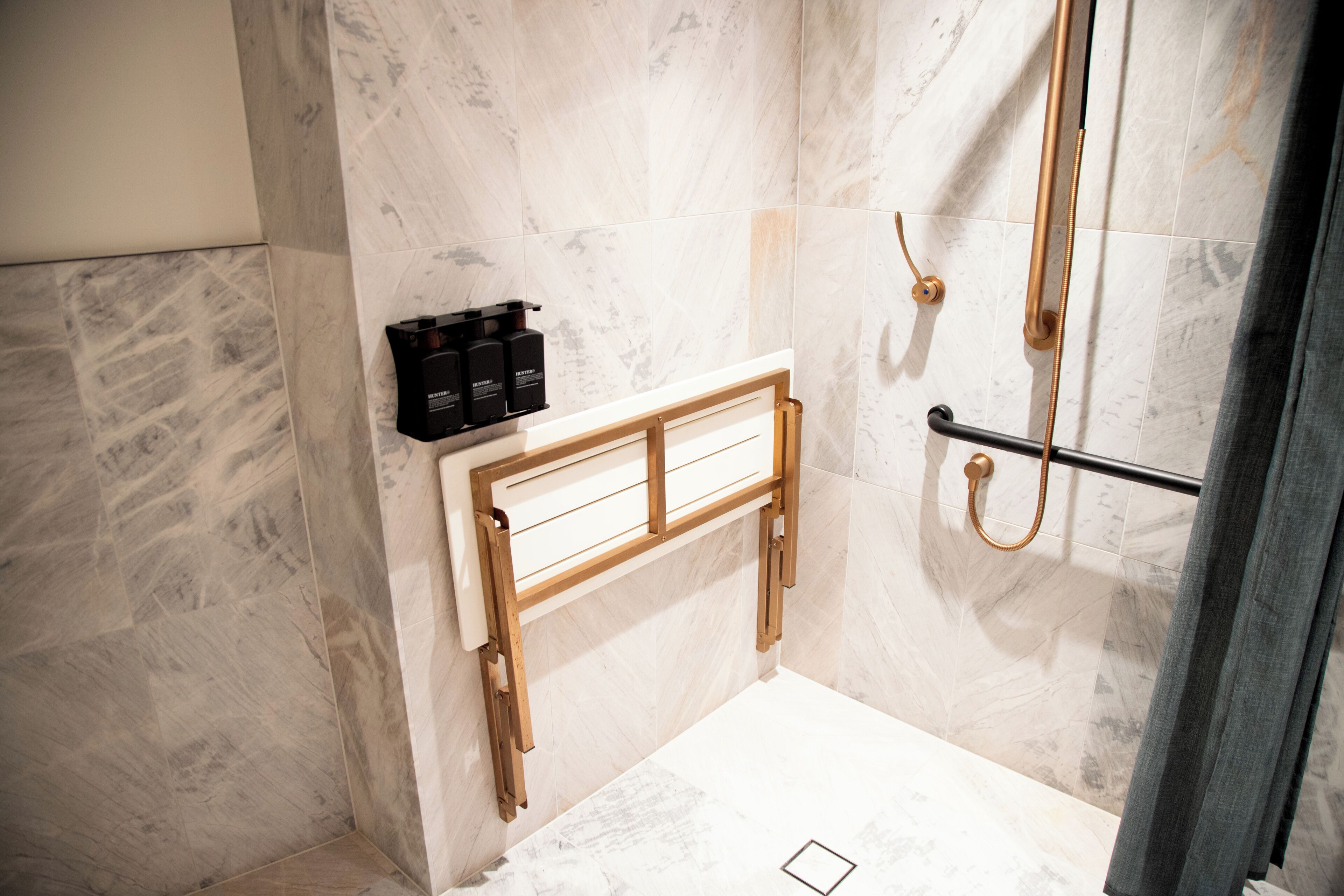 Un baño con ducha, un banco de madera y un perchero para toallas.
