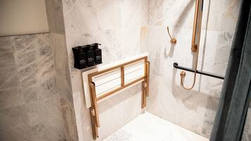 Un baño con ducha, un banco de madera y un perchero para toallas.