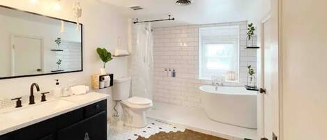 A modern bathroom with a white sink, black vanity, white toilet, and a shower area.