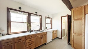 Una cocina moderna con armarios de madera, un lavamanos doble y un amplio ventanal que proporciona luz natural.