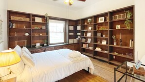 Un dormitorio con cama, ventilador de techo y estanterías empotradas.