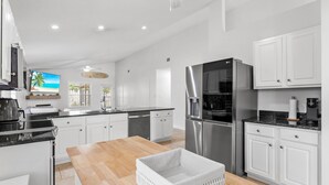 Una cocina moderna con armarios blancos, electrodomésticos de acero inoxidable y una mesa de comedor de madera.