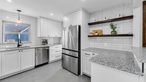 Una cocina moderna con armarios blancos, electrodomésticos de acero inoxidable y encimeras de granito.