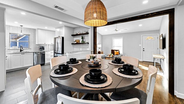 Una cocina moderna con armarios blancos, una mesa de comedor con cuencos negros y una lámpara colgante de mimbre.