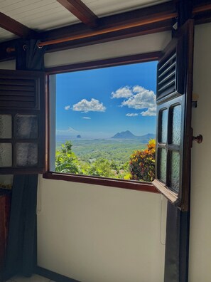 Ein Zimmer mit Fensterblick auf eine gebirgige Landschaft.