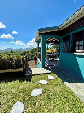 Ein Gebäude mit überdachter Terrasse und Blick auf die Landschaft, ein Tisch mit Stühlen.