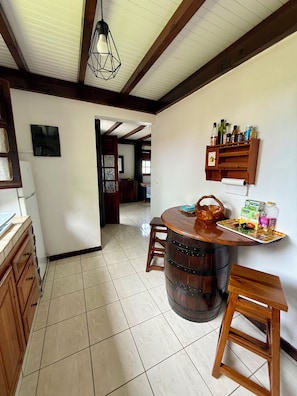 A kitchen with a wooden barrel table, a hanging light fixture, and a wall-mounted shelf with bottles. - VILLAS PAMEYAQUE / LA YAQUE with a pool and a magnificent view of the Caribbean Sea (Rivière-Salée)