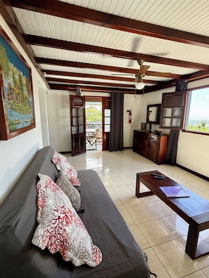A spacious living area with a sofa, a wooden coffee table, and a view through a doorway to an outdoor patio. - VILLAS PAMEYAQUE / LA YAQUE with a pool and a magnificent view of the Caribbean Sea (Rivière-Salée)