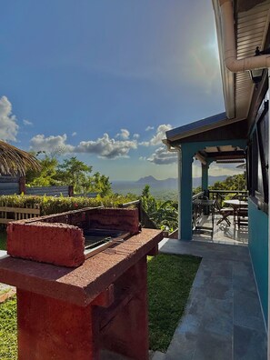 A patio with a barbecue grill, a covered seating area, and a view of mountains.