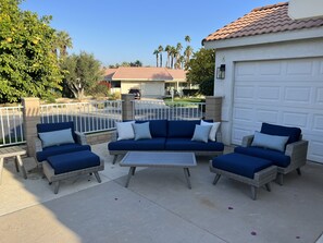 Relax on the patio with a sofa set and armchairs, surrounded by lush greenery.