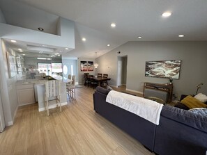 Relax in this open-plan living space with a central kitchen island and dining area, featuring a large sofa and abstract art.
