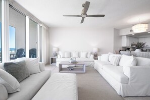 Un salon moderne avec un ensemble de canapés blancs, une table basse et un ventilateur de plafond.