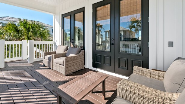 A covered porch with wicker furniture, a bench, and a door with a window. - Ocean View ☀️1 Lot from the Gulf | 52 10-Star Reviews | Beach Gear ☀️Comm Pool (Santa Rosa Beach)