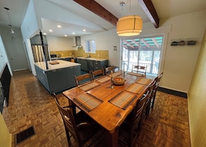 A kitchen/dining room with a wooden dining table, chairs, and a hanging light fixture.