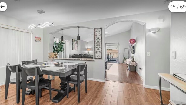 Een moderne keuken met een centraal eiland, een eethoek met tafel en stoelen, en een hal die leidt naar een woonkamer.