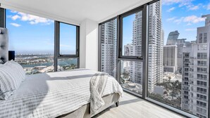 Una camera da letto moderna con un letto grande, vista sulla città e un'ampia finestra.