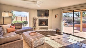Ein Wohnzimmer mit Kamin, Deckenventilator und einer großen Schiebeglasdoor zu einer Terrasse.