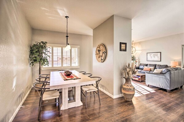 A dining area with a wooden table and chairs, a hanging light fixture, and a large potted plant. - Hot Tub Mountain View Getaway in Tucson! (Tucson)