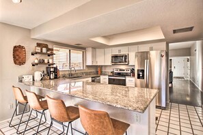 A modern kitchen with granite countertops, stainless steel appliances, and bar stools. - Hot Tub Mountain View Getaway in Tucson! (Tucson)