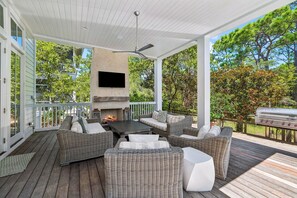 A covered outdoor patio with wicker furniture, a fireplace, and a flat-screen TV. - Private Pool + 6 Seat Golf Cart that is Close to SandHill Pool - WaterColor | Lake District Home (Santa Rosa Beach)