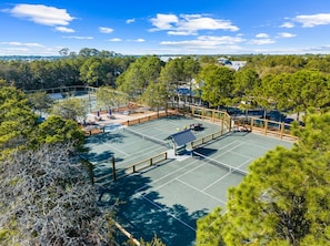 A tennis court surrounded by trees and a gazebo.
