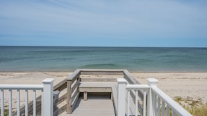 A wooden boardwalk leading to a beach with a clear view of the ocean.