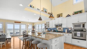 A spacious kitchen with a large island, white cabinetry, and a view to the outside.