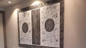 Un salon moderne avec un téléviseur à écran plat posé sur une console sombre, une œuvre décorative accrochée au mur au-dessus, et un petit vase avec des fleurs blanches sur la console.