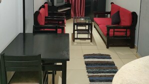 A living room with a TV, two sofas, a dining table, and a ceiling fan. - Al Dahar apartments Hurghada  (Hurghada)