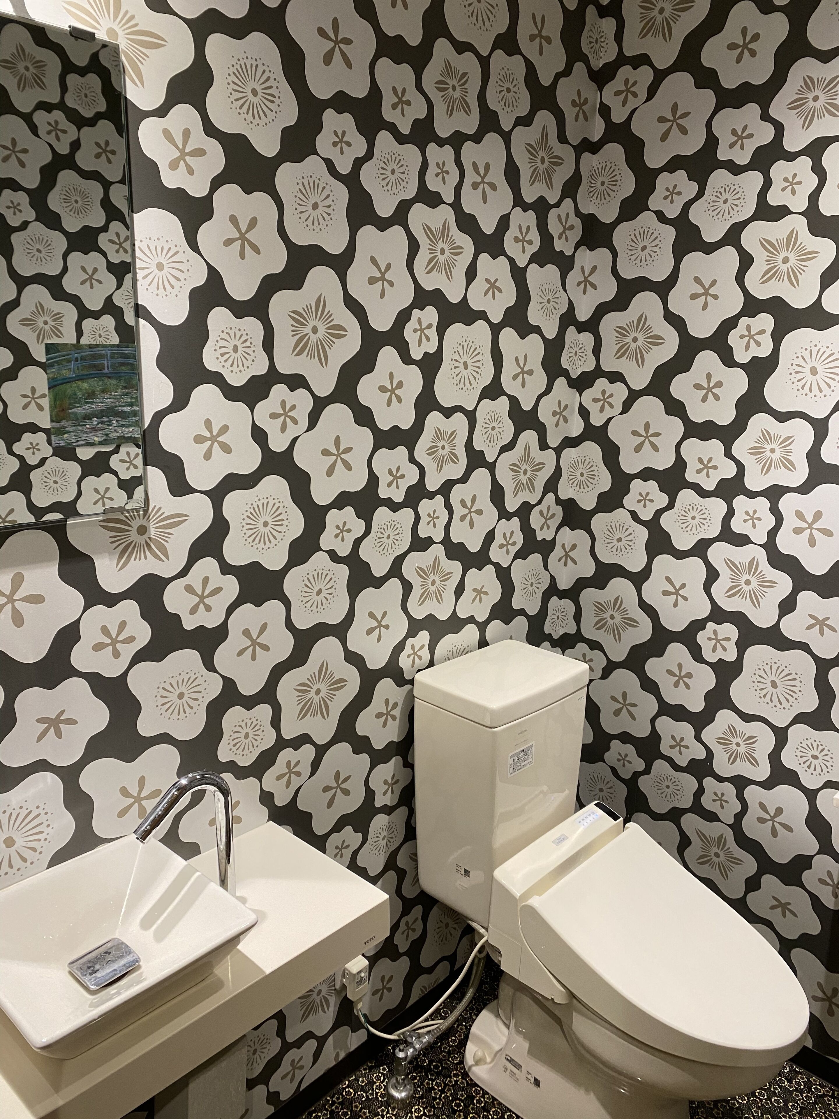 A bathroom with a toilet, sink, and a mirror.