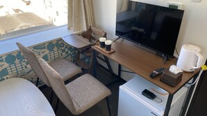 A compact hotel room with a TV, a small fridge, a coffee maker, and a seating area with a table and chairs. - HOTEL WAKO Tokyo Tree View (Tokyo)