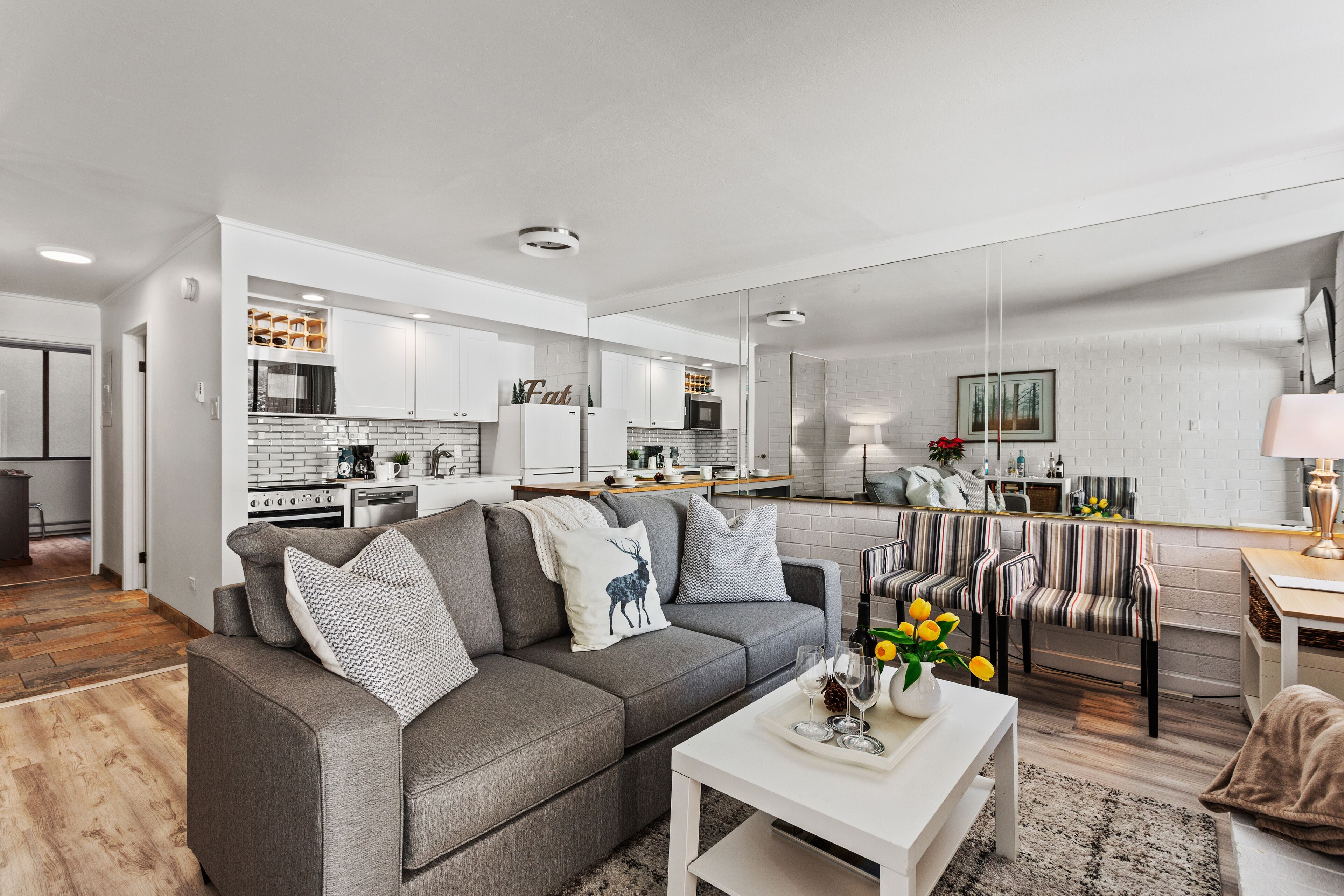 A modern living room with a grey sofa, a coffee table, and striped chairs.