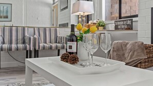 A modern living room with striped sofas, a white coffee table with a bottle, glasses, and a pine cone. - Great Location for Year-Round Recreation & Luxury Community Amenities + Pet-Friendly! (Park City)