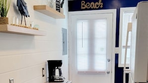 Una cocina con encimera de madera, una cafetera y una decoración de pájaro en la pared.