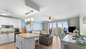 A modern kitchen with white cabinets, a central island, and a dining area with a table and chairs. - Living Right, Ocean View, 5 Pools, Beach Access at Laketown Wharf 1016 (Panama City Beach)