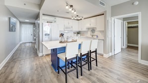 Une cuisine moderne avec des meubles blancs, un îlot central doté de chaises et un coin repas.