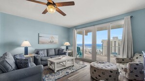 A living room with a ceiling fan, a sofa, a coffee table, and a view of the ocean through large sliding glass doors. - Beachy King at Laketown Wharf 812 | Remodeled 8th Floor Condo with Ocean Views and 5 Pools (Panama City Beach)