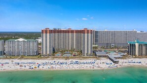 A beachfront hotel complex with multiple high-rise buildings, a sandy beach with umbrellas, and clear blue skies. - Hook Wine & Sinker - Beachfront Condo, 6th Floor (Panama City Beach)