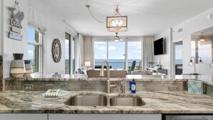 A modern kitchen with a large island, double sink, and a view to the outside. - Hook Wine & Sinker - Beachfront Condo, 6th Floor (Panama City Beach)