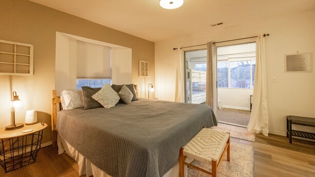 A bedroom with a large bed, bedside lamps, a bench, and a view through a sliding door. - 3BR Fall Creek Condo Near Table Rock Lake + Branson Attractions | FC 39-2 (Branson)