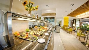 Un área de bufé con diversas opciones de comida y un espacio de comedor con sillas amarillas.