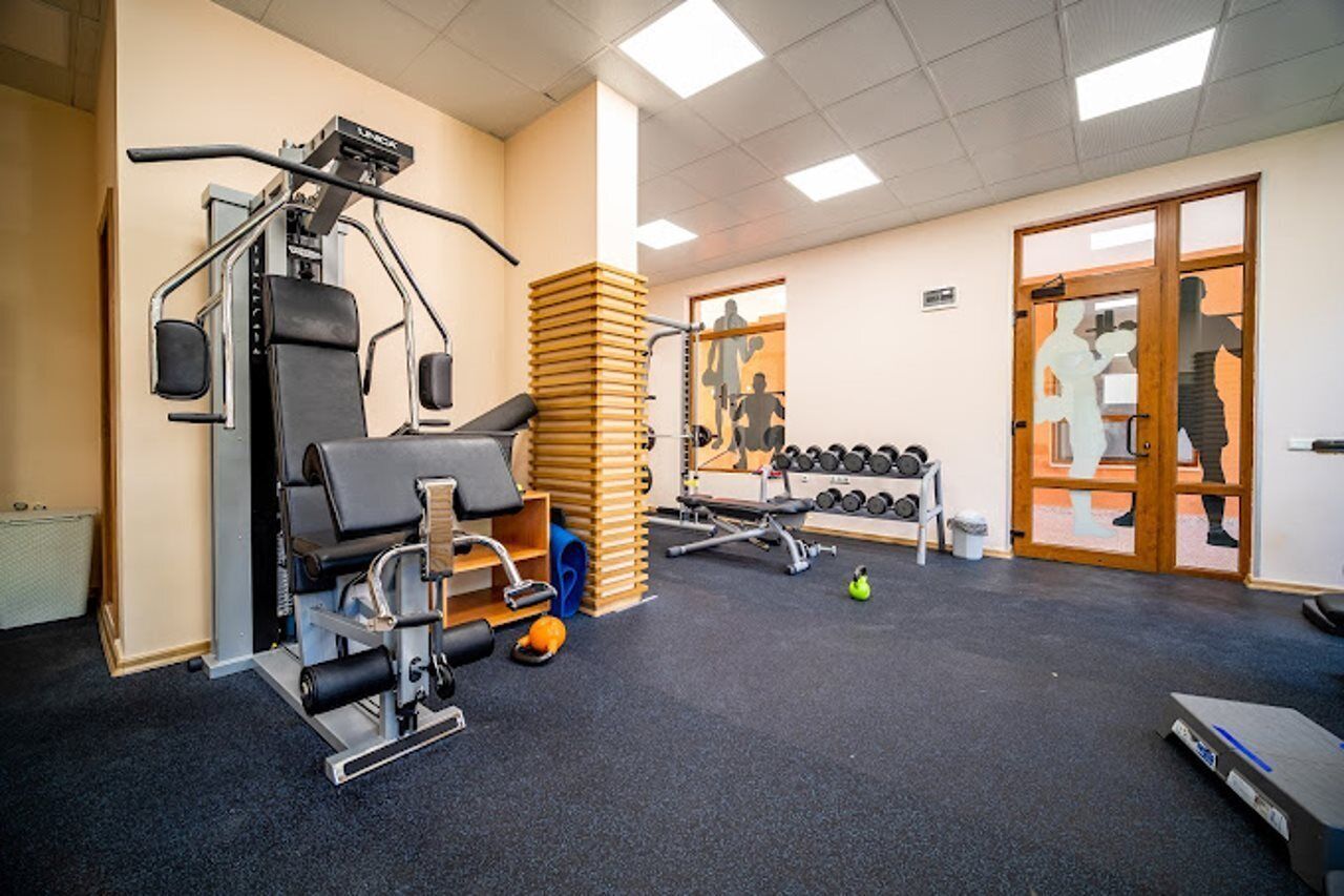 Una palestra con attrezzature per esercizi, uno specchio e una porta che conduce in un'altra stanza.